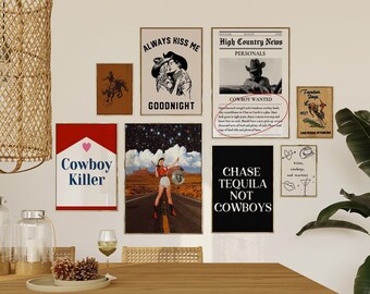 May include: A collection of eight framed prints with various western-themed designs, including a cowboy wanted poster, a couple kissing, a woman in a desert landscape, and a cowboy hat with the text "Chase Tequila Not Cowboys". The prints are hanging on a white wall above a wooden table with wicker chairs.