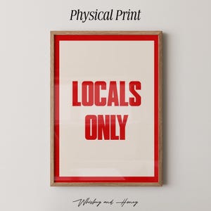 Op de afbeelding: Een ingelijste print met een rode rand en de woorden "LOCALS ONLY" in vette rode letters op een crèmekleurige achtergrond. De woorden "Physical Print" staan bovenaan en "Whiskey and Honey" onderaan.