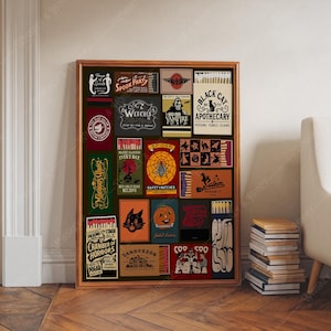 May include: A framed collection of vintage matchbox labels with Halloween themes. The labels feature illustrations of witches, spiders, black cats, and pumpkins. Text includes "Spook Party," "Black Cat Apothecary," and "Chamber of Horrors."