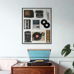 Op de afbeelding: Een zwart-wit ingelijste print van vintage technologie-items, waaronder een televisie, een typemachine, een cassettebandje, een computer, een camera, een platenspeler en een filmrol. De print hangt aan een witte muur boven een houten tafel met een platenspeler erop.