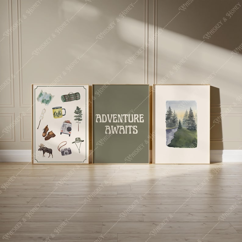May include: Three framed prints with a nature theme. The left print features a white background with illustrations of camping gear, including a map, a sleeping bag, a mug, a campfire, and a moose. The center print has a green background with the text "Adventure Awaits". The right print features a watercolor painting of a forest scene with a river.