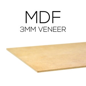 May include: A light brown MDF (Medium Density Fiberboard) sheet with a 3mm veneer. The text "MDF" and "3MM VENEER" are printed in black. The sheet is angled, showing its edge and surface.