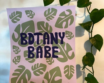 Könnte beinhalten: Eine rosa Karte mit einem grünen Blatt-Muster und dem Text "BOTANY BABE" in lila Schrift.