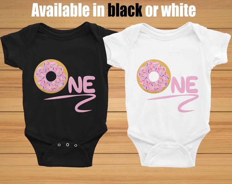 May include: Two baby onesies, one black and one white, with a pink donut and the word "ONE" printed on them.