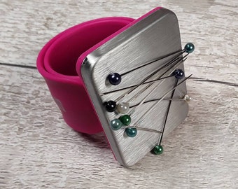 Prym Arm Magnetic Pin Cushion on a pink snap band for pins and small metal items while sewing and crafting.