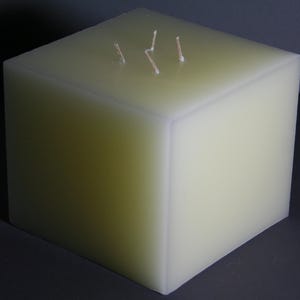Könnte beinhalten: Eine große, quadratische, cremefarbene Kerze mit drei Dochten.
