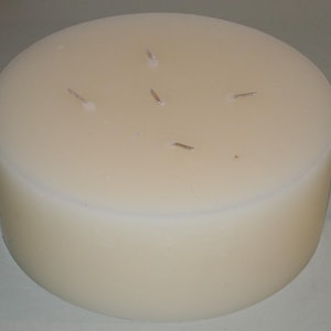 May include: A large, round, white pillar candle with four wicks.