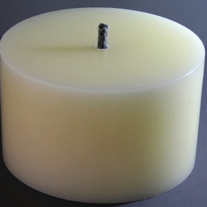 May include: A plain white pillar candle with a black wick.