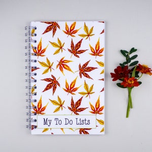 May include: A white spiral bound notebook with a colorful fall leaf pattern and the text "My To Do Lists" on the front cover.