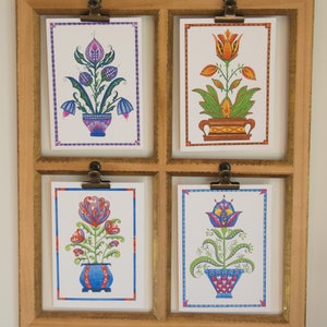 May include: Four framed art prints featuring colorful stylized floral designs. Each print depicts a different flower in a pot with a unique pattern. The flowers are in shades of pink, orange, red, and blue.