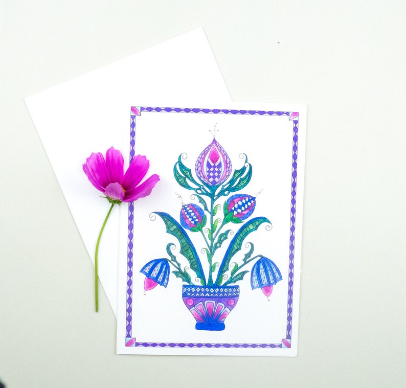 May include: A hand-drawn illustration of a stylized floral design with blue, green, and pink flowers in a blue and white patterned pot. The illustration is framed with a purple border.