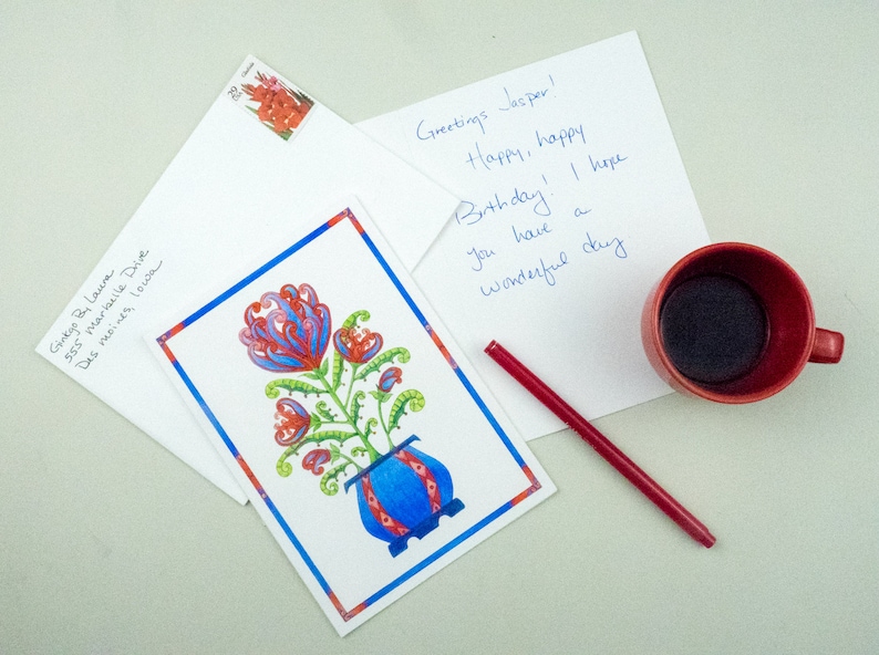 May include: A birthday card with a colorful floral illustration in a blue and red pot. The card has a handwritten message that says "Greetings Jasper! Happy, happy Birthday! I hope you have a wonderful day."