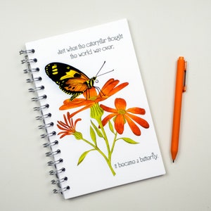 May include: A white spiral bound journal with a quote about a caterpillar turning into a butterfly. The quote reads "Just when the caterpillar thought the world was over, it became a butterfly." The journal features a colorful illustration of a butterfly on a flower.