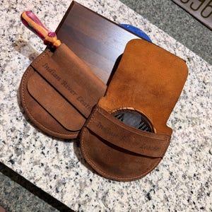 May include: A set of three ceramic mugs with a speckled, matte finish. The mugs are in shades of cream, light gray, and dark gray. Each mug has a simple, modern design and a rounded handle. The mugs are stacked on top of each other.