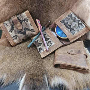 May include: Several leather wallets with snake skin pattern accents are displayed. The wallets are brown with a square shape and a snap closure. Also included are a few colorful tools.