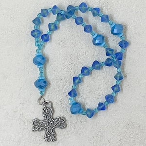 May include: A blue and light blue glass beaded rosary with a silver cross charm.