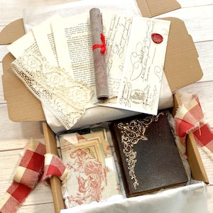 May include: An open cardboard box filled with vintage ephemera. Includes a rolled scroll tied with red ribbon, aged paper, lace, a small book with gold filigree, and fabric with a red and white pattern. A red and white checkered ribbon is also included.