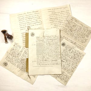 May include: An assortment of antique documents and letters with handwritten text in faded ink. A wooden and metal wax seal and inkwell are visible. The papers are arranged on a white surface, suggesting a historical or vintage theme.
