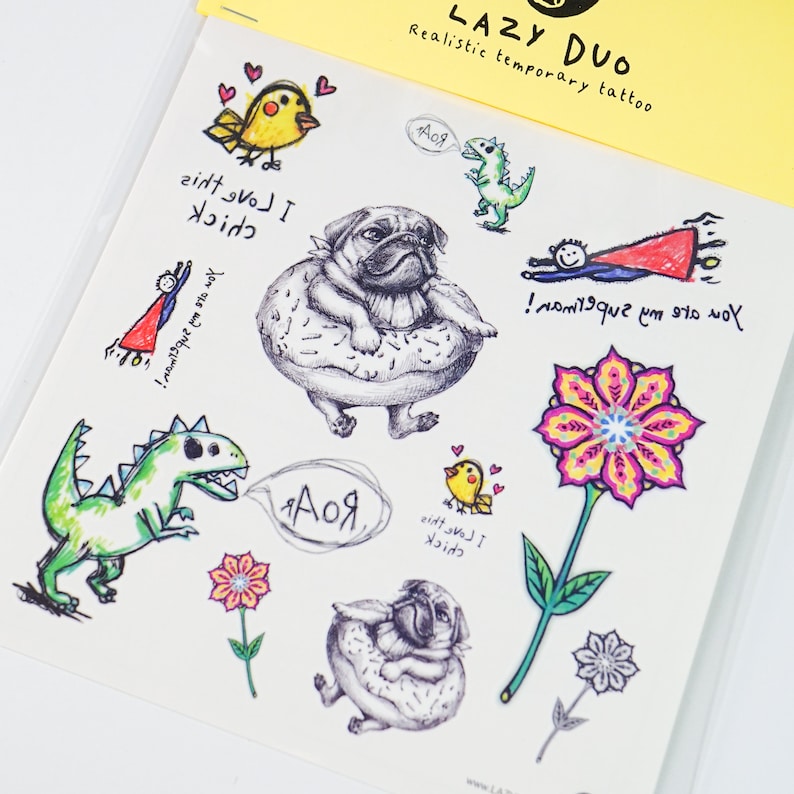 May include: A sheet of temporary tattoos with cartoon illustrations. Designs include a pug in a donut, dinosaurs, flowers, birds, and a superhero. The text "LAZY DUO" and "Realistic temporary tattoo" are visible.
