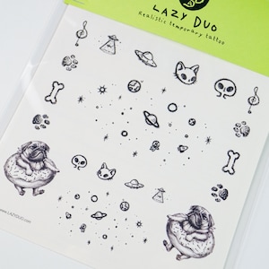 May include: A sheet of temporary tattoos with a variety of designs, including a pug wearing a donut, a cat, a skull, a UFO, a planet, stars, and a bone. The sheet is white with black ink and the text "LAZY DUO Realistic temporary tattoo" at the top.