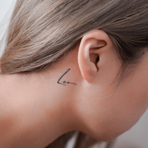 May include: A close-up of a person's ear with a small tattoo that says "Leo" behind the ear.