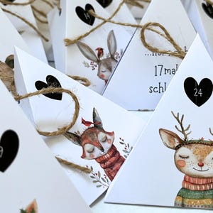 May include: White triangular advent calendar boxes with heart-shaped cutouts and twine ties. Each box features a different woodland animal illustration, including a deer, fox, and rabbit, with numbers inside the hearts.