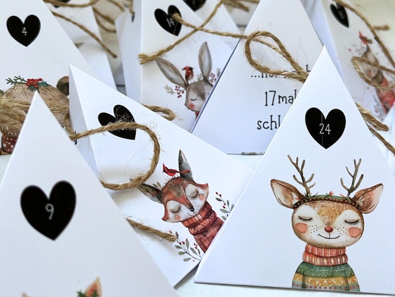 May include: White triangular advent calendar boxes with heart-shaped cutouts and twine ties. Each box features a different woodland animal illustration, including a deer, fox, and rabbit, with numbers inside the hearts.
