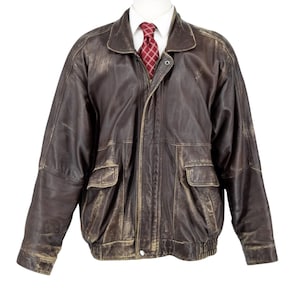 May include: A dark brown leather jacket with a distressed finish, featuring a collared neckline, long sleeves, two front flap pockets, and a front zipper closure. A white collared shirt and a red tie with a white grid pattern are worn underneath.