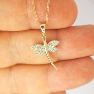 以下が含まれることがあります： 金色のトンボペンダントネックレス。 トンボの羽にはクリスタルのようなアクセントがあります。 ネックレスは繊細なゴールドチェーンに付いています。 ペンダントの長さは約2.5cmです。