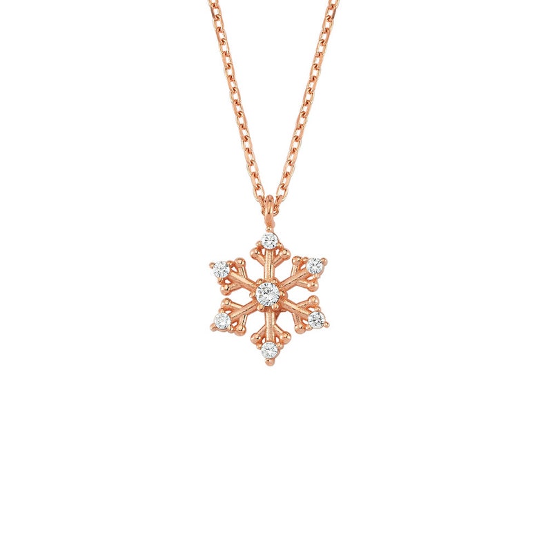 May include: A delicate gold snowflake necklace with clear sparkling stones. The necklace features a delicate chain and a snowflake pendant with a center stone and smaller stones around the edges.