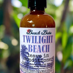 May include: A brown bottle of "Beach Babe Twilight Beach leave in conditioner" with a black spray nozzle. The label features a palm tree graphic and the text "Vegan Cruelty Free Handmade in the USA 4.0 ounces".