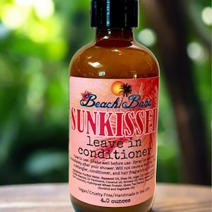 May include: A brown bottle of Beach Babe Sunkissed leave-in conditioner with a black spray top. The label is pink with the product name and instructions. The bottle contains 4.0 ounces of product.