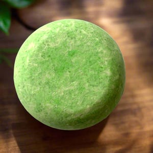 May include: A round, green solid shampoo bar with a marbled appearance.