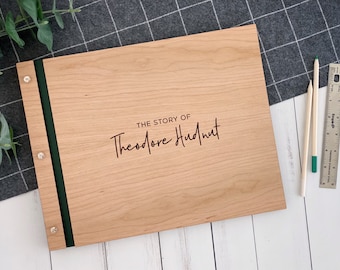 Könnte beinhalten: Ein Holzfotoalbum mit einem grünen Band und dem Text "THE STORY OF Theodore Hudnut" auf der Vorderseite.