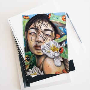 May include: Watercolour painting of a woman with long dark hair and red eyes. She is surrounded by green and red frogs and white water lilies.