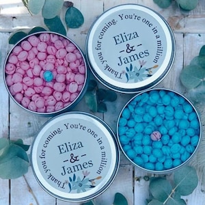 May include: Two silver tins filled with pastel pink and blue candy. The tins have labels that say "Thank you for coming. You're one in a million. Eliza & James".