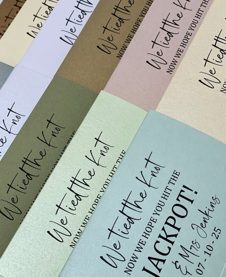 Puede incluir: Una pila de sobres de color azul claro, blanco, verde, marr&oacute;n, rosa y crema con el texto "We tied the knot" y "Now we hope you hit the jackpot!" impreso en ellos.