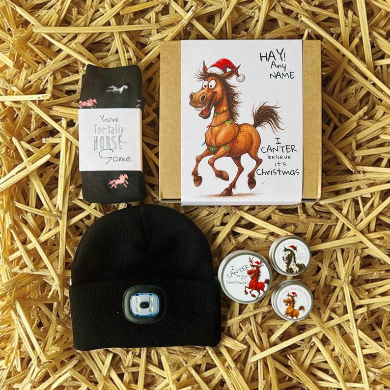 May include: A gift set with a Christmas theme, featuring a black beanie with a light, a pair of black socks with horse graphics, and a greeting card with a cartoon horse wearing a Santa hat. The set also includes three small tins.