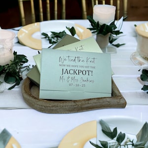 Puede incluir: Una tarjeta verde claro con el texto "We tied the knot. Now we hope you hit the JACKPOT! Mr. & Mrs. Jenkins 07-10-25" en letras negras.