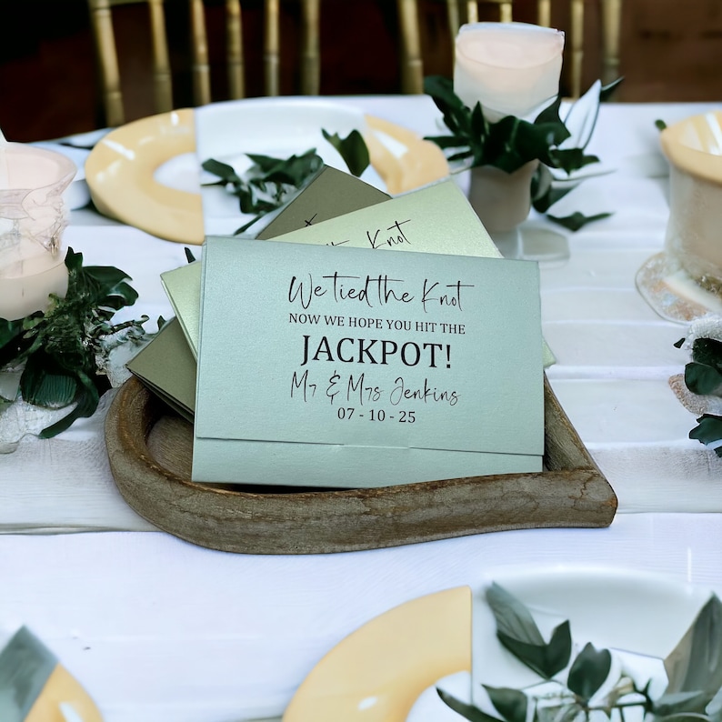 Puede incluir: Una tarjeta verde claro con el texto "We tied the knot. Now we hope you hit the JACKPOT! Mr. & Mrs. Jenkins 07-10-25" en letras negras.
