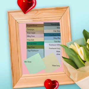 Puede incluir: Una tabla enmarcada con muestras de color de diferentes tonos de marr&oacute;n, rosa, verde, azul, blanco y marfil. La tabla est&aacute; rodeada por un marco de madera y dos corazones rojos. La tabla est&aacute; titulada "Recycled Brown" en la parte superior izquierda y "Matte Ivory" en la parte inferior derecha.