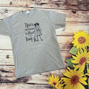 Puede incluir: Camiseta gris con un gr&aacute;fico negro de una mujer con el texto "Nunca subestimes el poder de un berrinche."