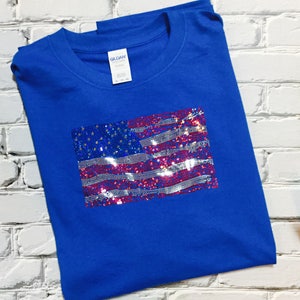 May include: A royal blue t-shirt with a sequined American flag design. The flag is made of red, white, and blue sequins.