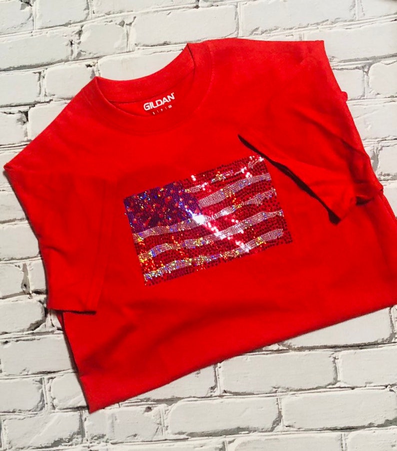 May include: Red Gildan t-shirt with a sequined American flag design.