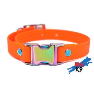 Puede incluir: Collar de perro de goma naranja con una hebilla arco&iacute;ris iridiscente. El collar tiene dos peque&ntilde;os puntos azules a cada lado de la hebilla.