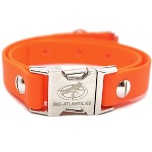 Puede incluir: Collar de perro naranja con una hebilla plateada. La hebilla tiene el texto "MID-ATLANTIC K9" y un logotipo de un perro corriendo con una br&uacute;jula.