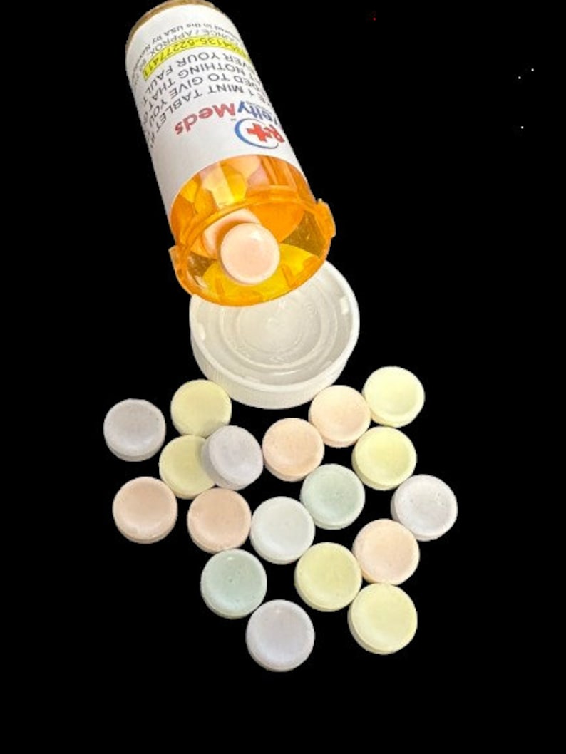 K&ouml;nnte beinhalten: Eine ge&ouml;ffnete Pillenflasche mit einem wei&szlig;en Deckel und einem Etikett mit der Aufschrift "MyMeds Minztablette Um Ihnen Nichts Zu Geben, Was Ihre Schuld Ist". Die Flasche versch&uuml;ttet runde, pastellfarbene Pillen.