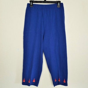 May include: Blue cropped pants with a red sailboat design on the bottom hem.