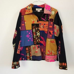 May include: A colorful patchwork jacket with a black background and embroidered details. The jacket has a button-up front and long sleeves. The label "ana" is visible on the collar.