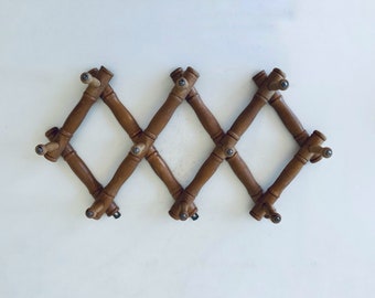 May include: A brown wooden wall-mounted coat rack with eight hooks arranged in a diamond pattern.